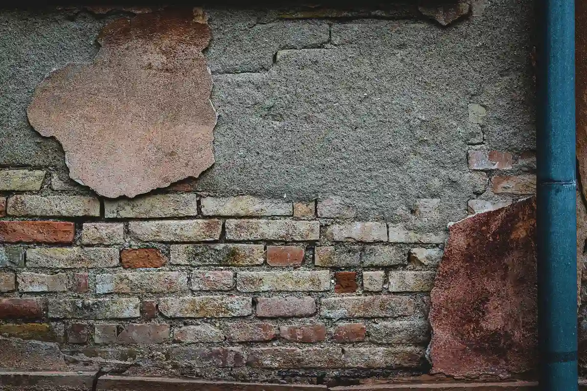 Before: Front facade — dated siding removed, stone veneer installed over proper drainage mat
