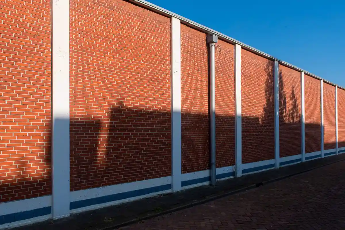 Before: Primary facade — plain concrete wall clad with anchored natural stone veneer panels