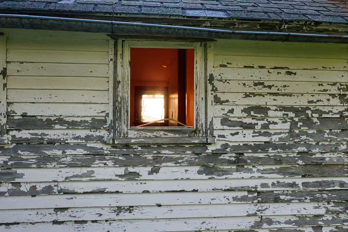 Before: Front facade — dated siding removed, stone veneer installed over proper drainage mat